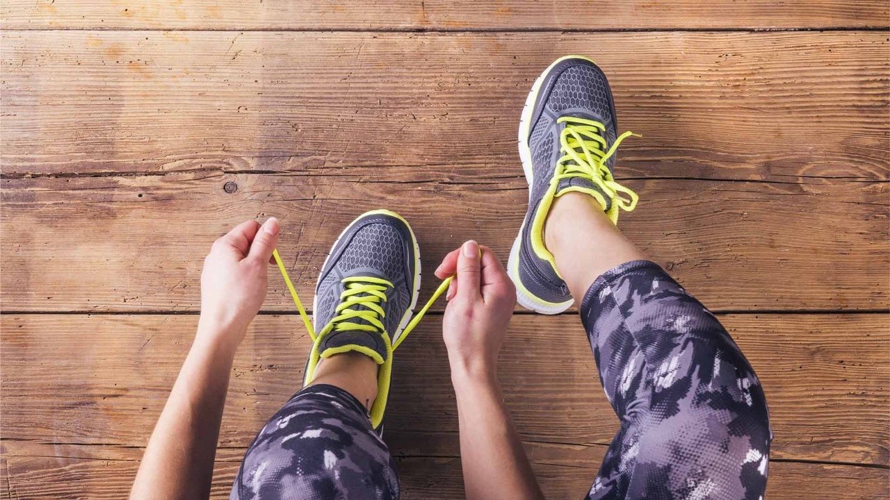 Person tying the shoelace of her running shoes from a top activewear brand in Singapore