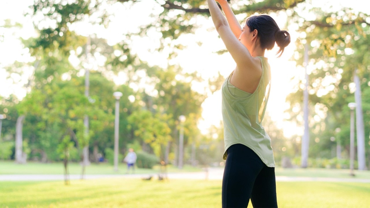 Woman in activewear attire, a loose fit top and black fitted leggings